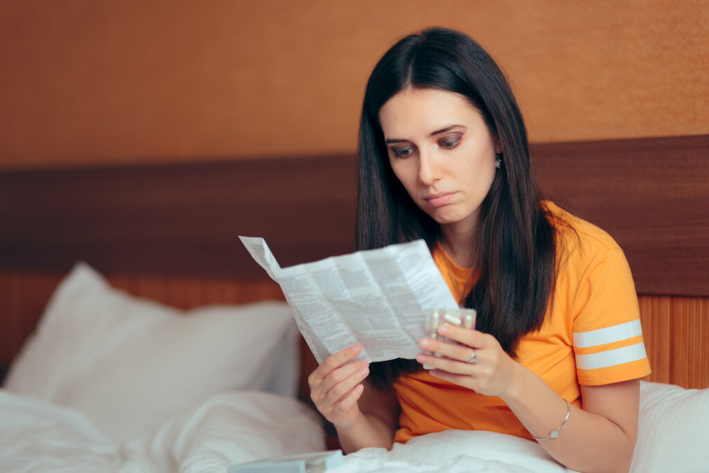 Woman reading medicine leaflet for possible health issues and side effects before taking prescription