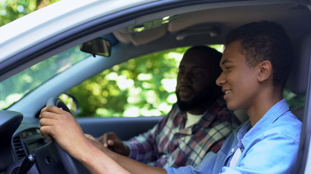 Parent teaching teen driver how to drive car