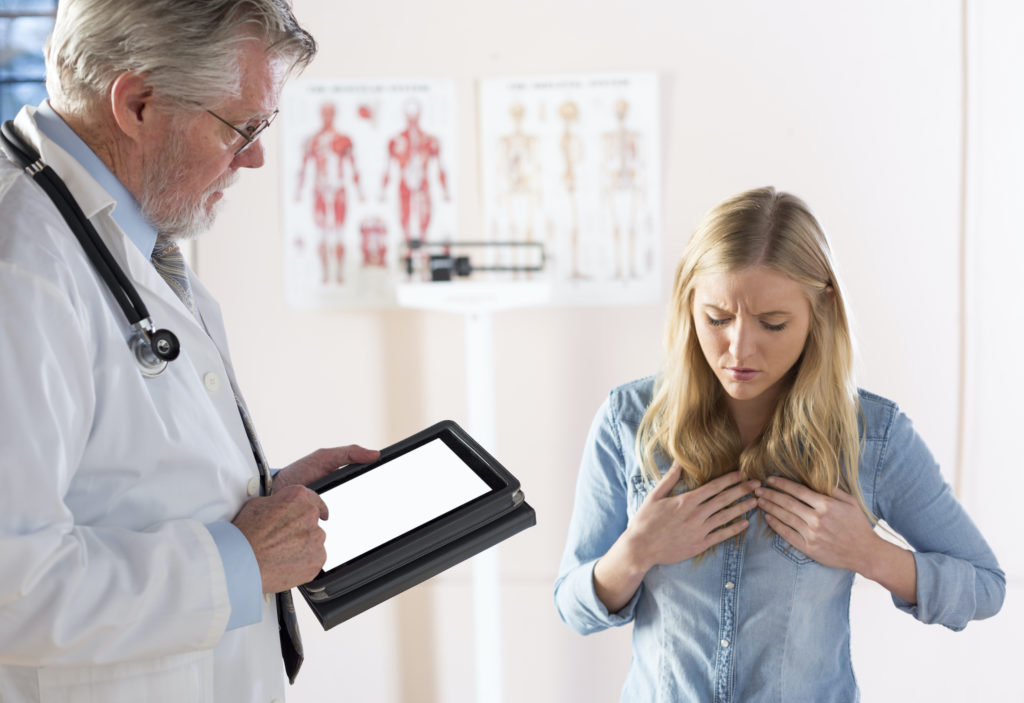 A young female patient describes her symptoms to her doctor.